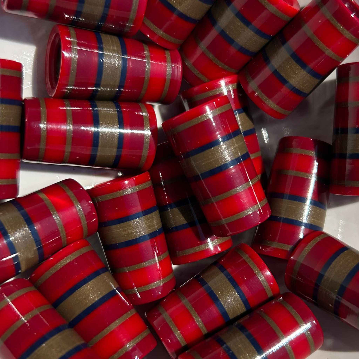 Pile of red, blue, and gold 3D-printed golf ferrules with various stripes.