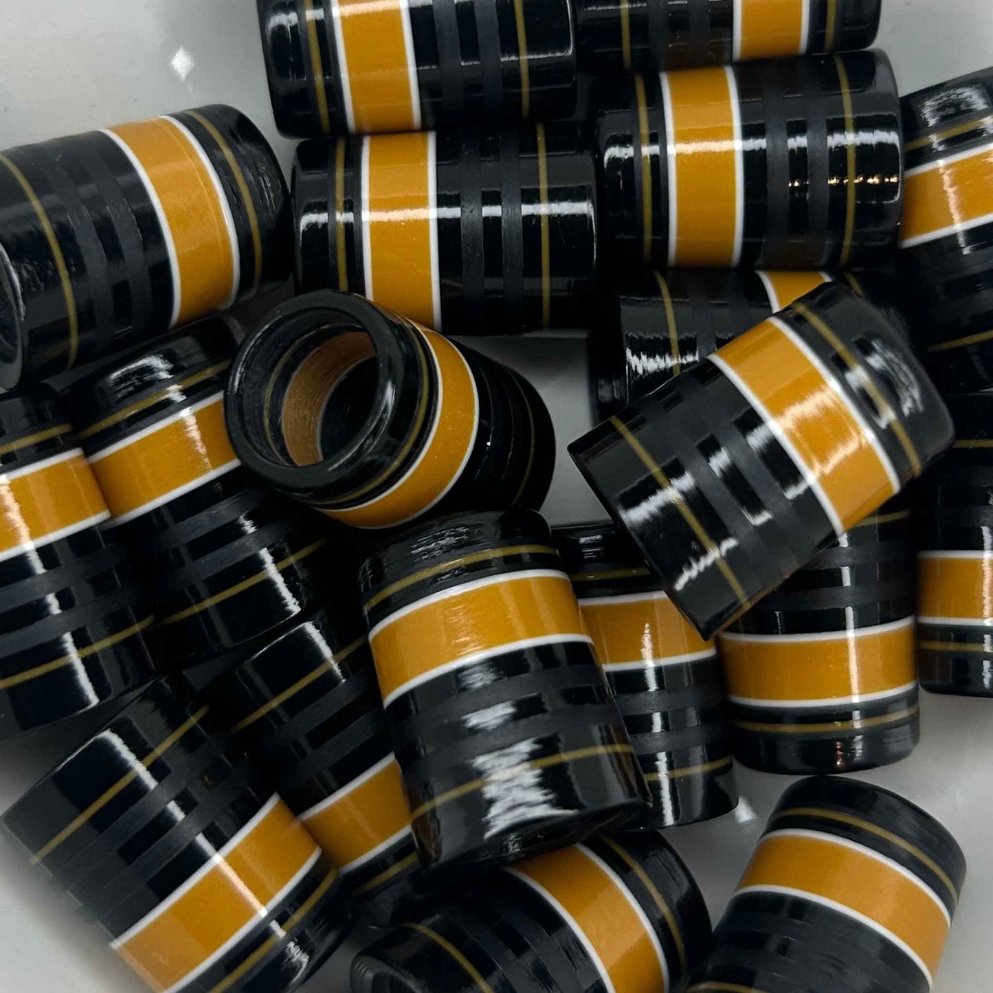 pile of three-quarter inch golf ferrules in black, with pops of gold and some matte black stripes