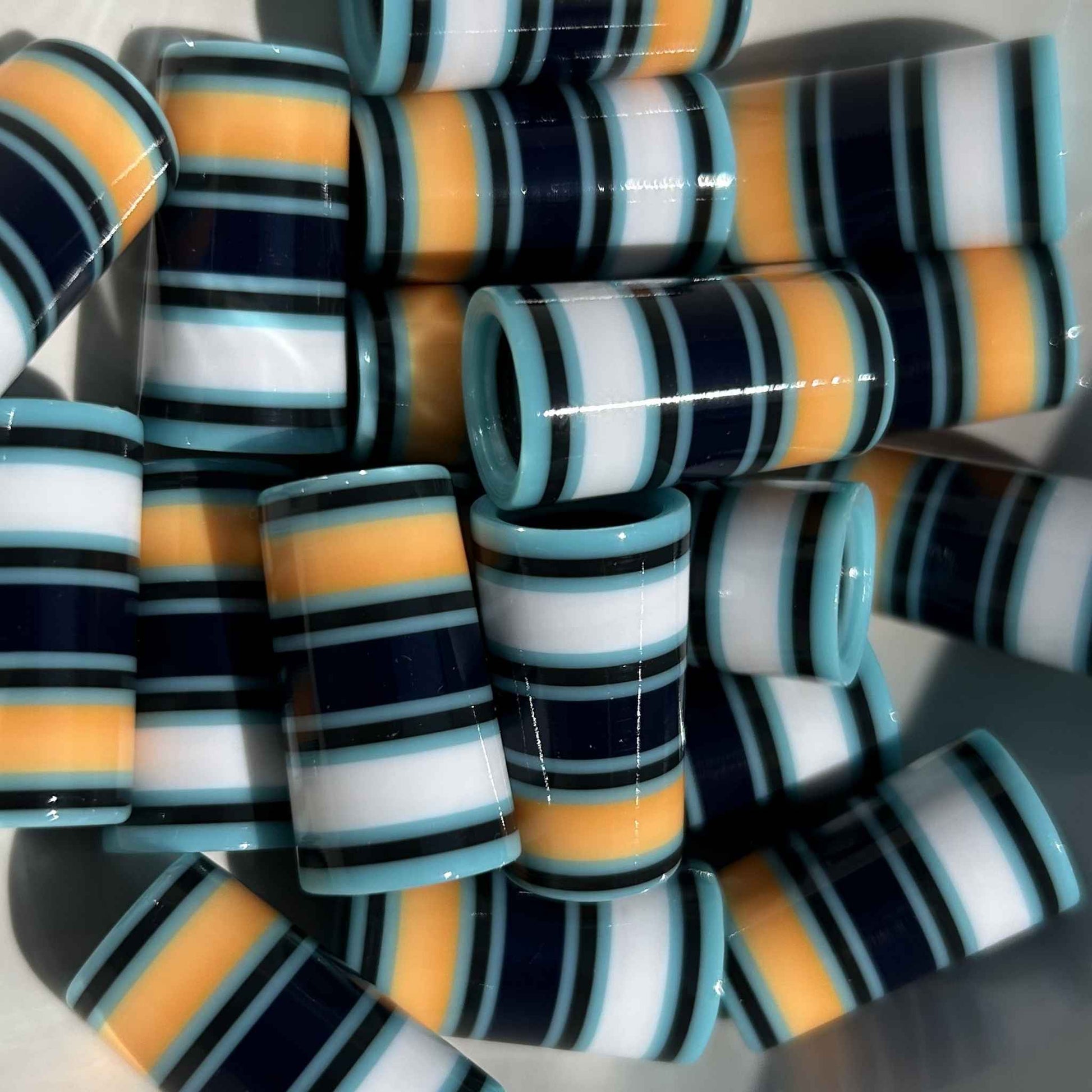 pile of Light Blue, Navy, White, and Orange golf ferrules with varying stripe thickness